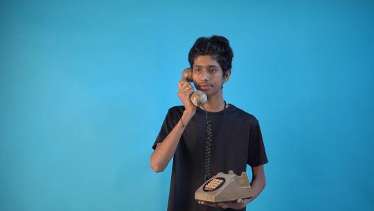 快乐兴奋的年轻印度人20多岁，穿着黑色t恤，拿着旧电话，刚刚找到你