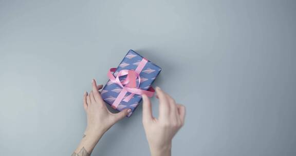 解开礼物盒上的粉色丝带