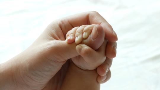 母亲的手抚摸着婴儿的脚