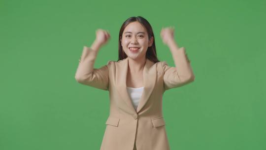 快乐的亚洲女商人站在绿色屏幕上庆祝在工作室视频素材模板下载