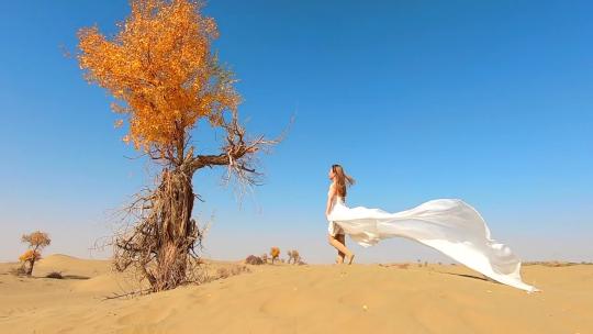 穿着白色长裙的美女行走在沙漠里