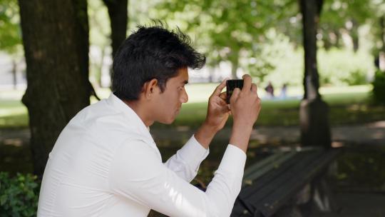 男子用手机拍摄公园的特写