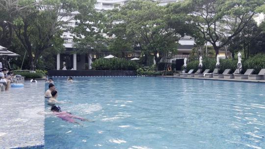 假日人们在度假酒店游泳池嬉戏