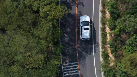 白色汽车行驶在公路滨海路林间穿梭弯路