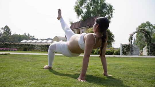 怀孕美女在花园里练习瑜伽母婴健身体操