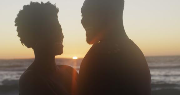 日落时分快乐的非裔美国夫妇在海滩上拥抱的视频