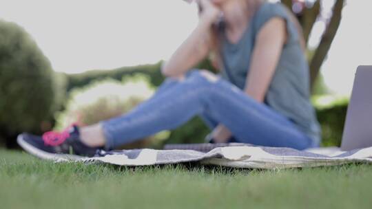 一个女人坐在户外草地毯子上