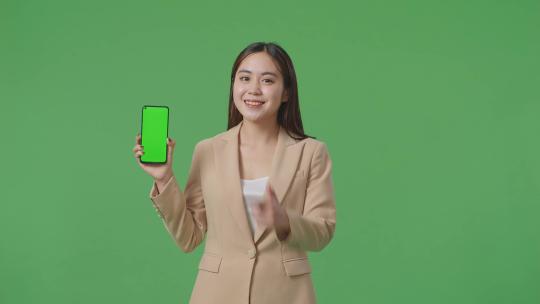 商务女性微笑着在绿屏上展示和指着绿屏手机