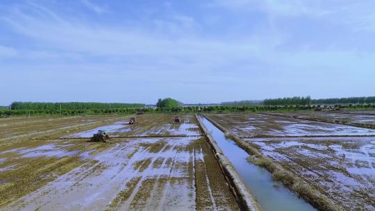 航拍拖拉机在稻田平整土地