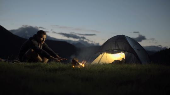 年轻人取暖与营火在自然山户外露营现场在夜间多莉
