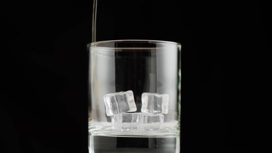 将威士忌倒入装有冰块的玻璃杯中的特写镜头