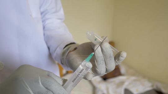 一名戴着手套的非洲医生在非洲准备将药物注入针头的特写镜头。
