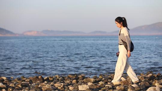 烟台大海黄昏日落，夕阳海边行走的女孩