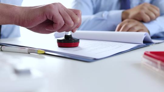 穿西服的商人达成合作协议并签字盖章握手