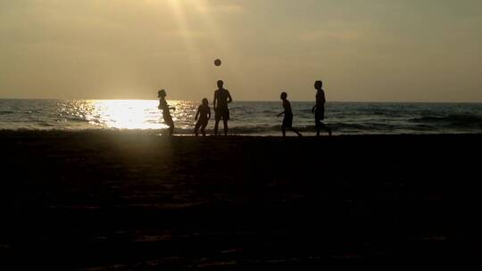 日落时分孩子们在海滩上踢球
