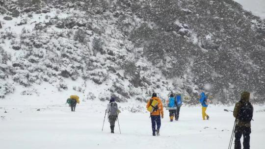 攀登岷山山脉都日峰的登山者在雪中徒步行进