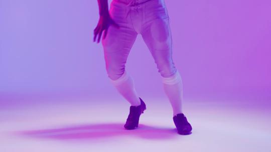 橄榄球运动员在紫色背景下运球