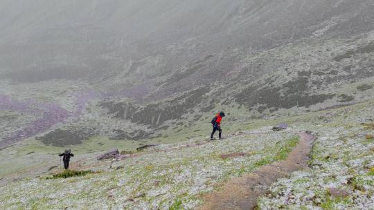 攀登甘孜那玛峰的登山者在冰雹中徒步行进