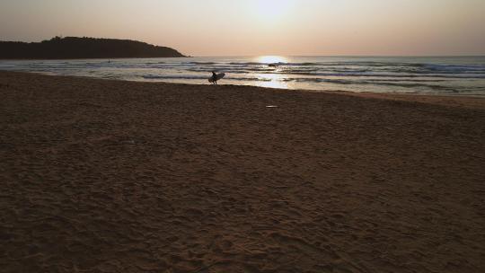 冲浪者在日出时到海上冲浪
