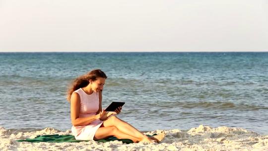 2438_年轻女子在沙滩上用平板电脑