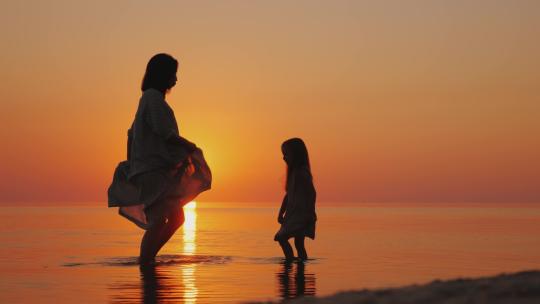 日落时分母女在海滩玩耍