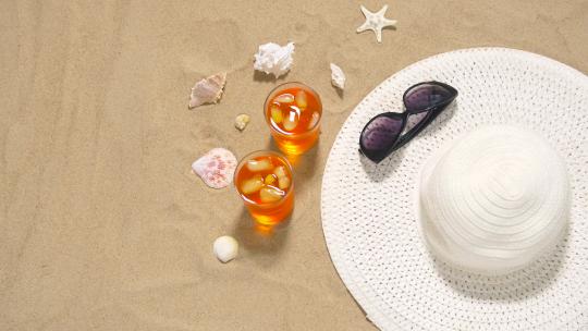 海滩沙滩上的鸡尾酒、太阳帽和太阳镜