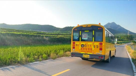 行驶在山上农村乡间小路上的黄色校车