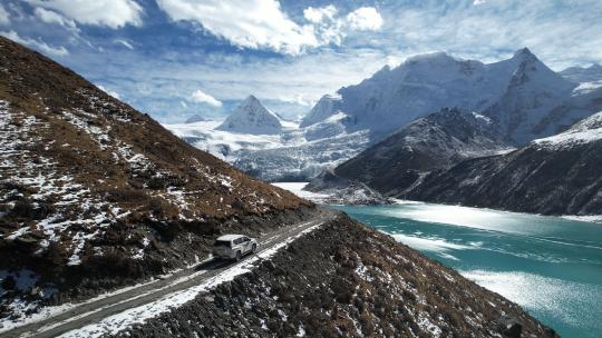 汽车行驶在西藏雪山湖泊边的土石公路