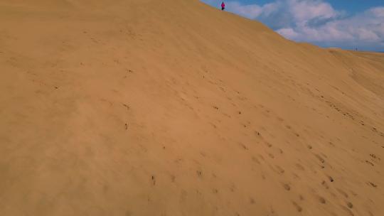 一个男人在沙丘上望着远处的大海