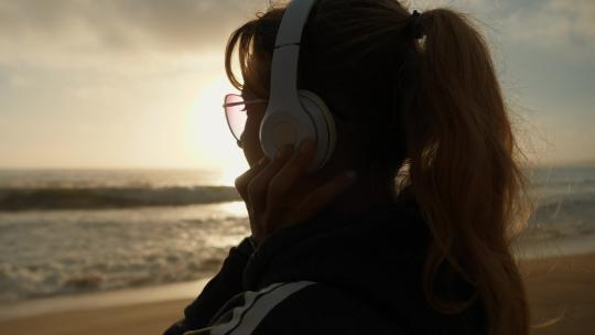 在沙滩上听音乐的女人