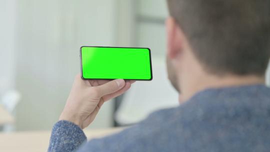 男人拿着带绿屏的水平智能手机