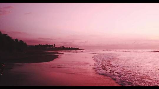 红色天空下海浪冲击海岸的视频