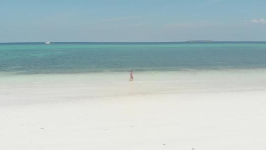女人走在白色沙滩上