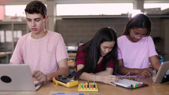 一群多元化的青少年学生在技术课上一起学习