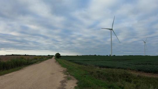 在乡村砾石路上开车时，看着大豆地里转动的风力涡轮机视频素材模板下载