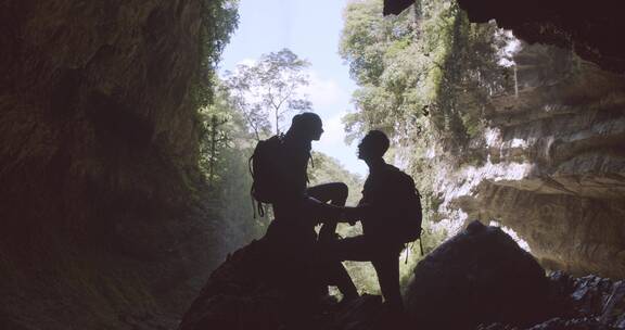 一对夫妇在瀑布后面的岩洞上休息