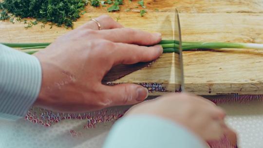 女人在木制砧板上切葱