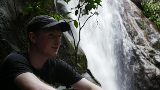 年轻的高加索男性在Ihla Grande Br的热带雨林徒步旅行时，在瀑布旁休息