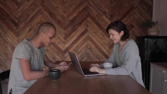 一个男人和一个女人一边使用他们的电子产品一边聊天