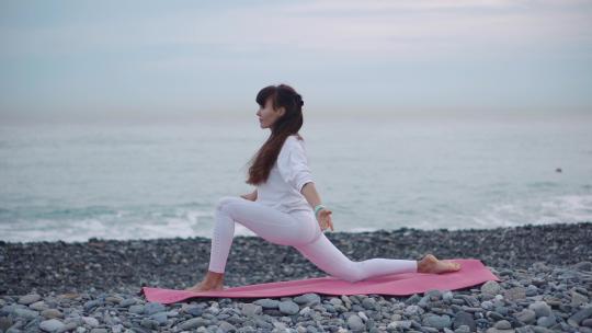 女运动员在卵石海岸练习瑜伽