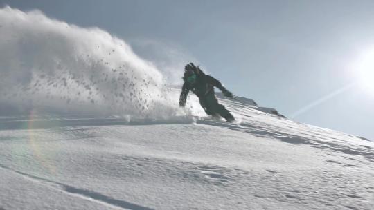 运动员从雪山顶踩着单板滑雪板滑雪