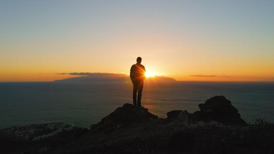 人站在岩石顶上日落光