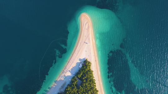 无人驾驶飞机飞越沿海地带、树木和岸上度假小镇克罗地亚的海滩
