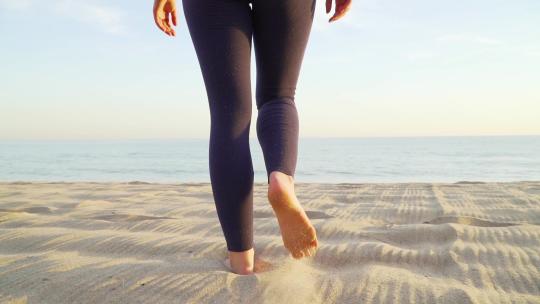 女性赤脚在海滩上走