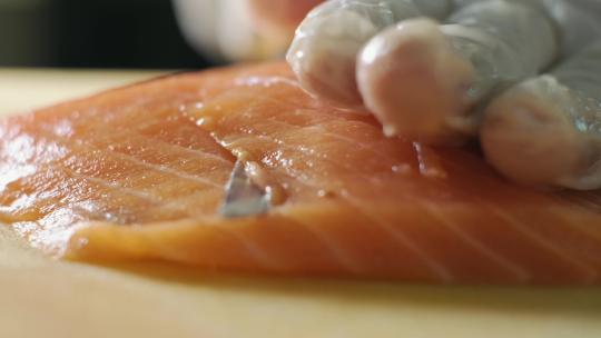 厨师用鱼片刀切新鲜橙色鱼肉的特写镜头