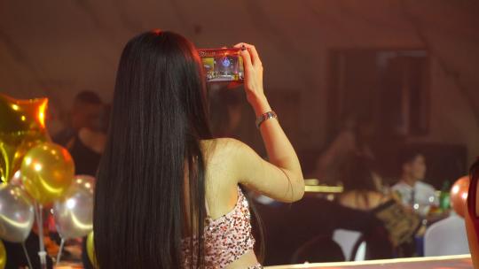 女孩在晚会现场用手机拍照