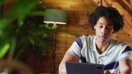 快乐的非裔美国人坐在桌旁，用平板电脑进行视频通话，慢动作
