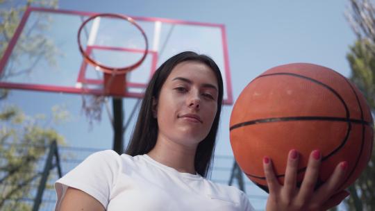 肖像可爱的青少年黑发女孩拿着篮球看着相机站着
