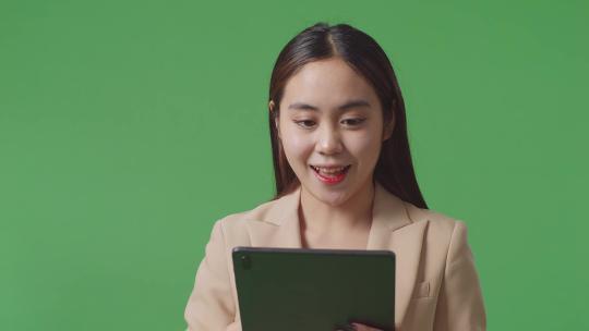 使用平板电脑并指向绿屏背景上的侧面的亚洲女商人特写镜头
