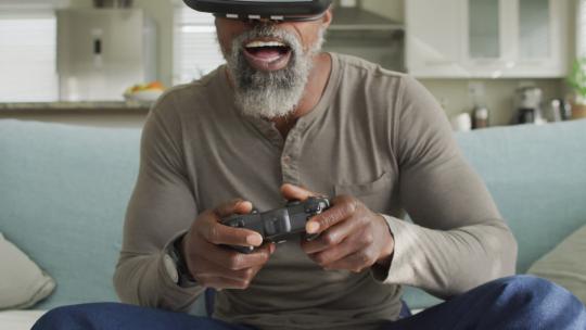 快乐的非裔美国人在家使用虚拟现实耳机玩电子游戏的视频